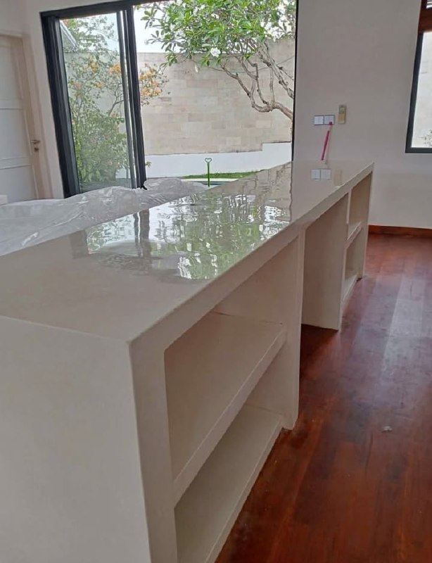 Countertop terazzo putih glossy panjang dengan shelving built-in di interior dekat jendela besar